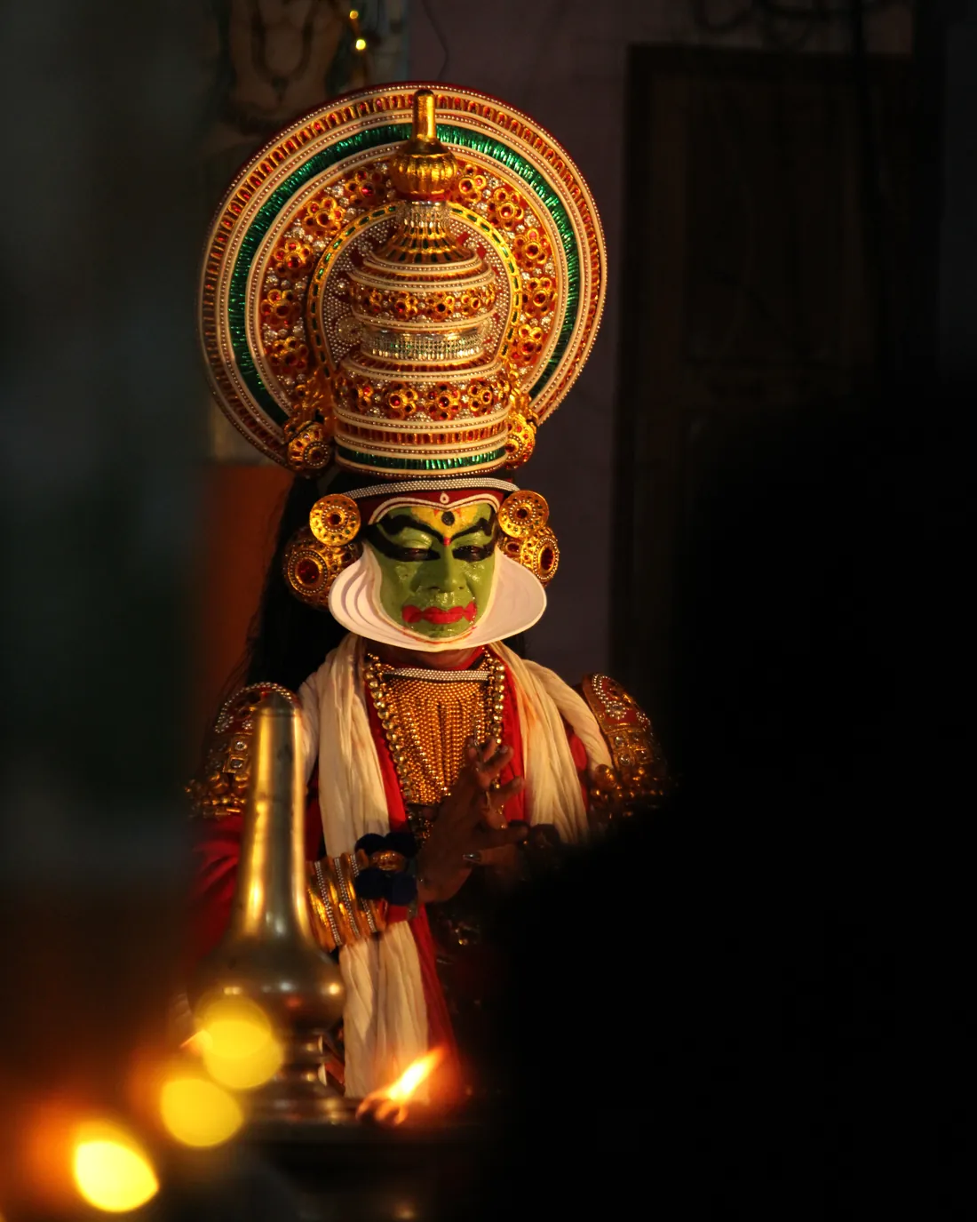 Detailní záběr na tvář a oči tanečníka Kathakali s propracovaným zeleno-červeným líčením